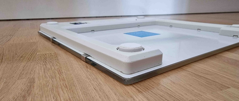 Körperfettwaage im Test befindet sich mit der Unterseite nach oben auf einem Holzboden.