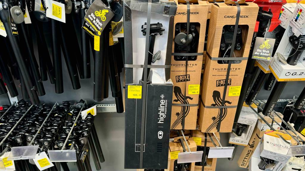 Absenkbare Sattelstütze im Test: Mehrere verpackte Geräte hängen zwischen anderen Produkten in einem Regal.