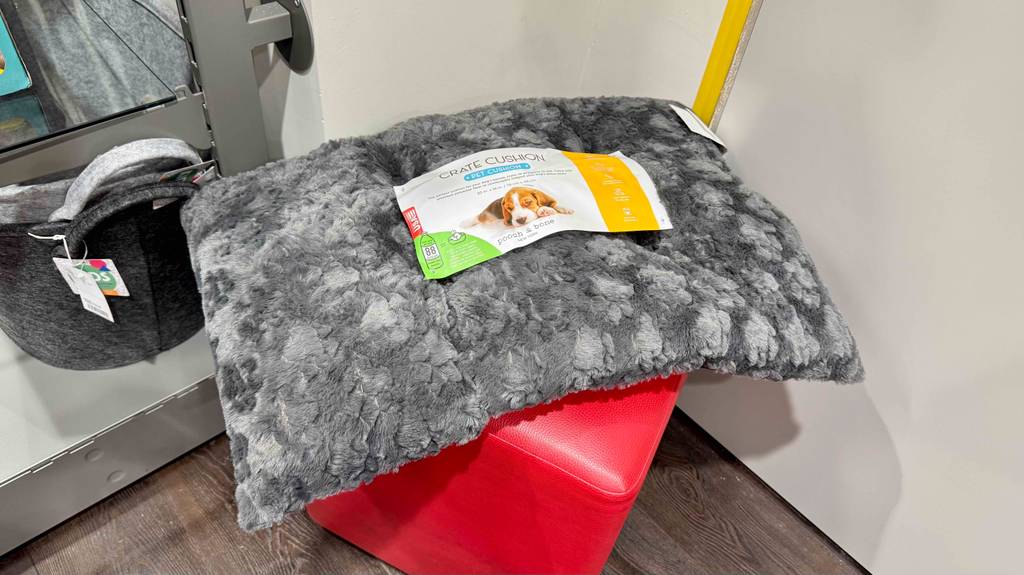 Hundekissen-Test: Ein graues, flauschiges, rechteckiges Kissen liegt auf einem roten Hocker.