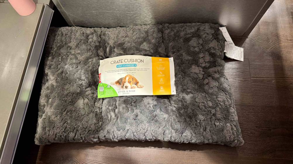 Hundekissen im Test: Ein graues, flauschiges, rechteckiges Kissen befindet sich auf einem braunen Boden