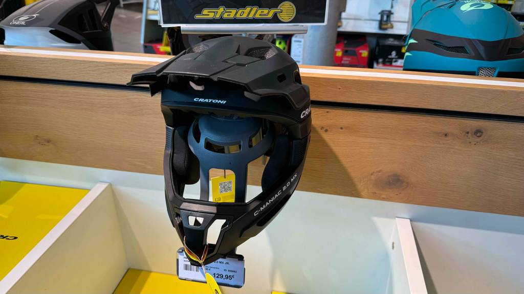 Frontansicht eines zum Testen an ein Holzregal gehängten Fullface-Helms.