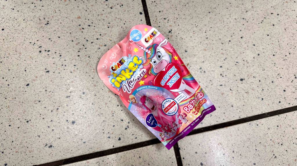 Eine Packung getesteter Badezusatz für Kinder liegt auf einem hellen Fliesenboden.