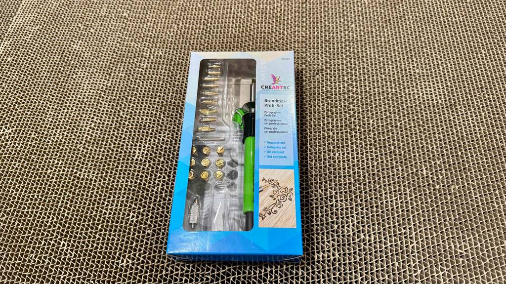Getestet: Das Brandmalerei-Set von Creartec liegt in einer Verpackung inklusive Sichtfenster auf einer braunen Pappoberfläche.