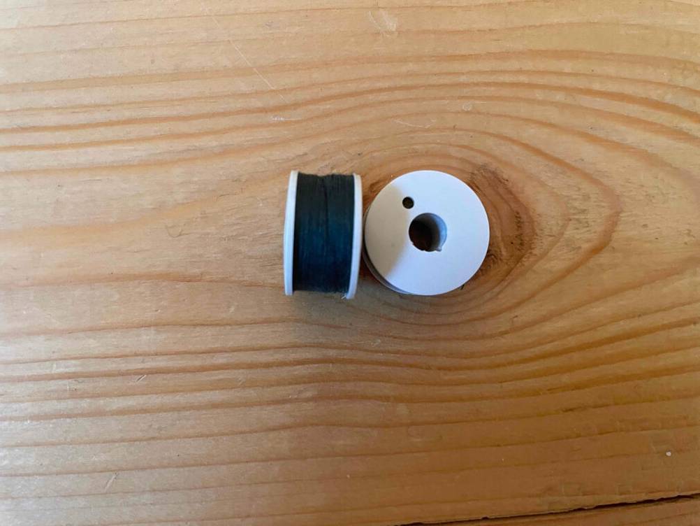Im Test: Zwei Rollen Nähgarn nebeneinander auf einer Holzfläche.