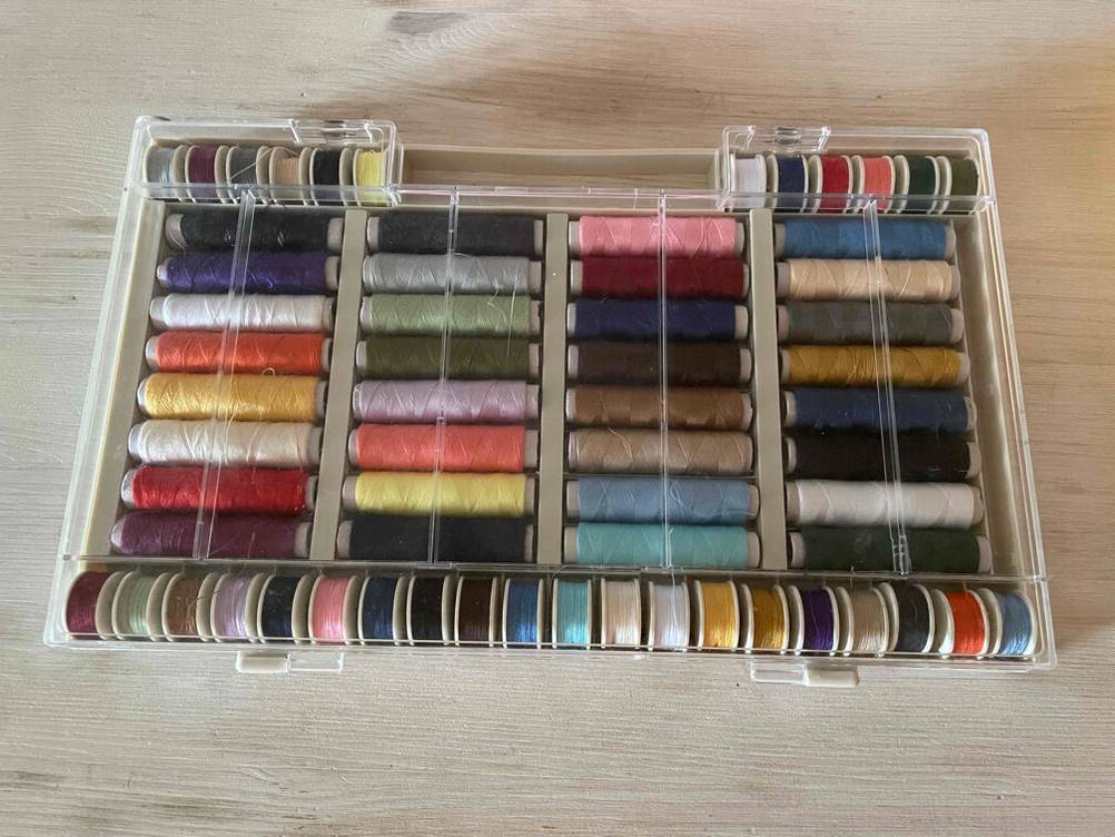 Nähgarn getestet: Eine transparente Box mit Nähgarn auf einer Holzfläche.