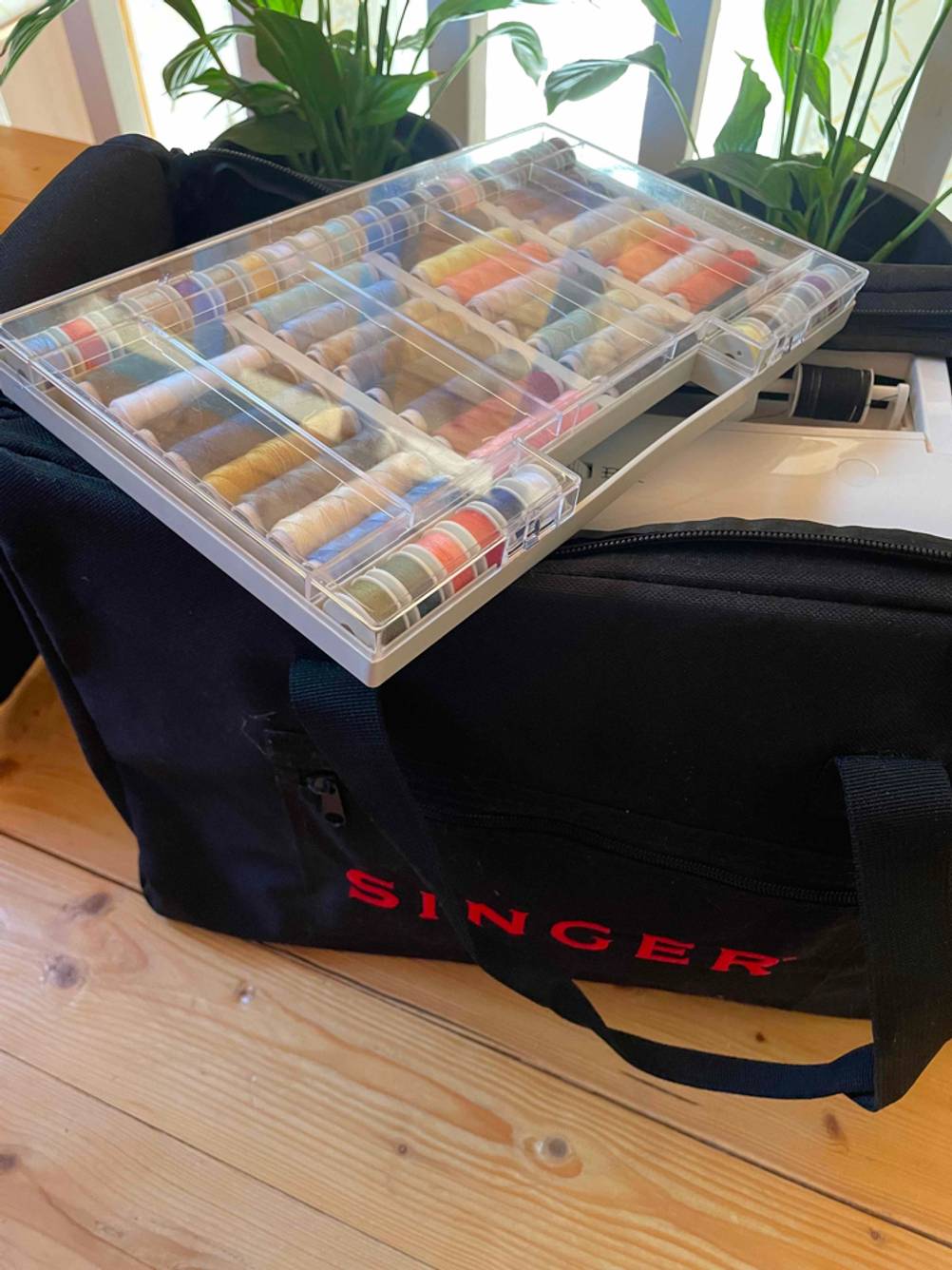 Nähgarn im Test: Ein Sortierkasten mit verschiedenen Garnen liegt schräg auf einer eingepackten Nähmaschine.