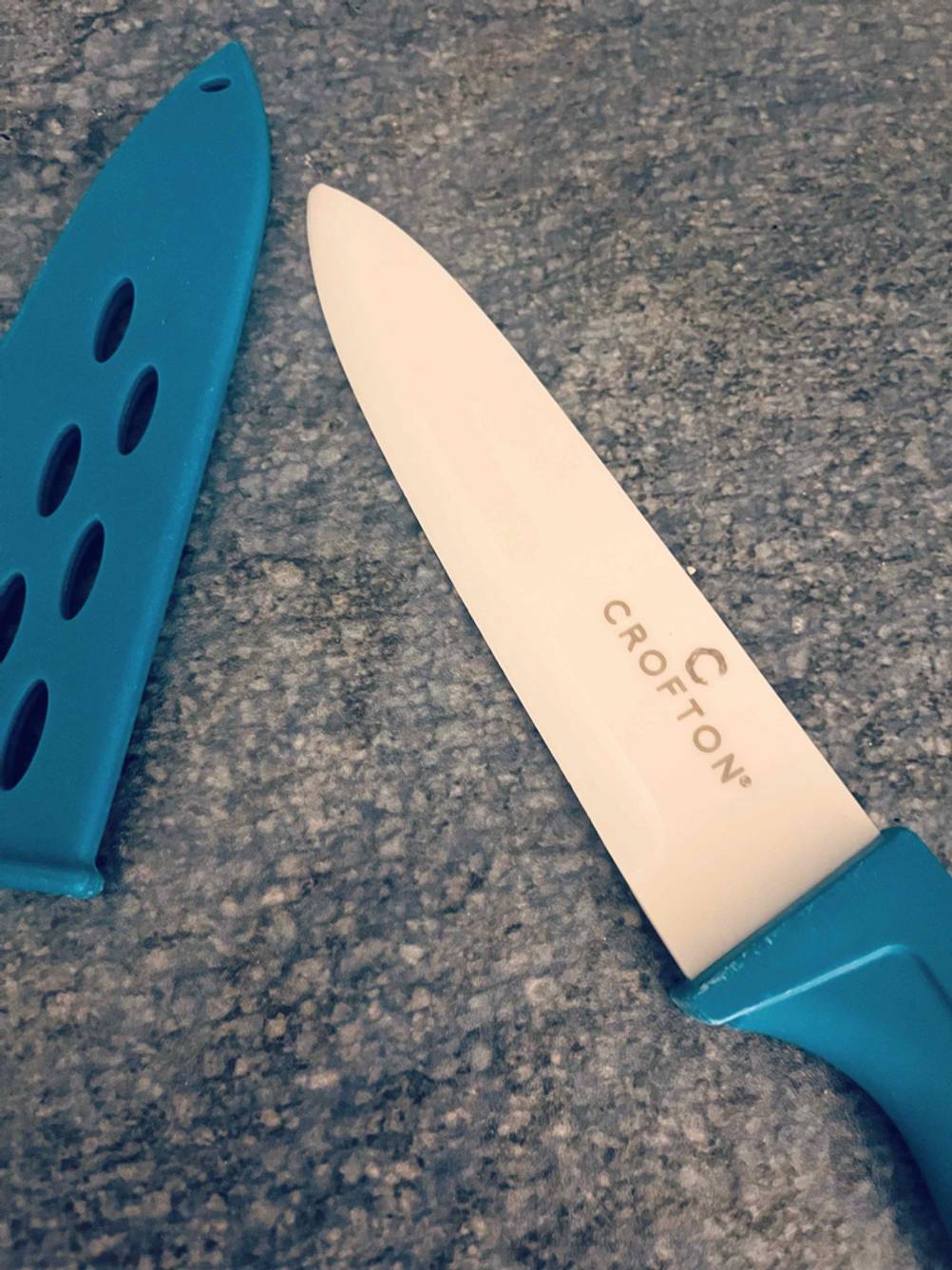 Im Test: Detailansicht der Klinge eines Keramikmessers, das neben der Schutzkappe liegt.