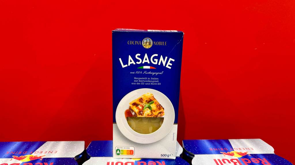 Getestete Lasagneplatten in der 500-g-Packung stehen in einem Verkaufsbereich auf Red Bull Dosen.
