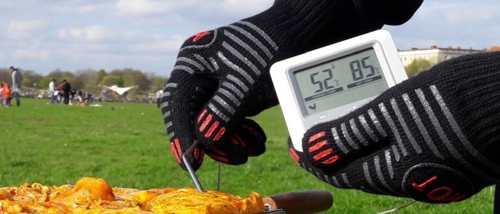 Mit Grillhandschuhen von Culinario wird ein Grillthermometer bedient.