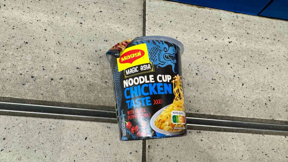 Auf einem Fließenboden liegt eine Packung der Cup-Noodles im Test.