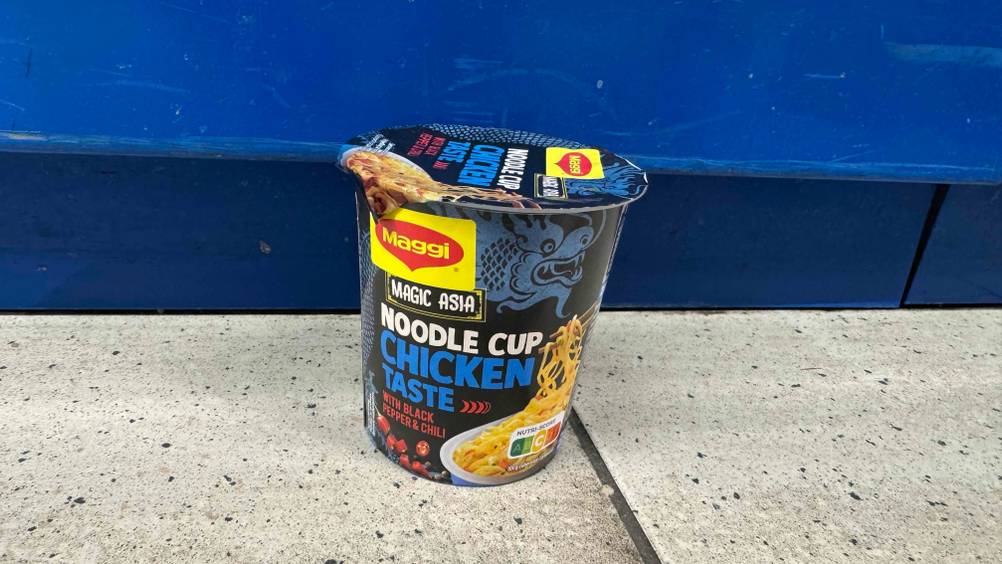 Vor einer blauen Fläche stehen die getesteten Cup-Noodles auf dem Boden.