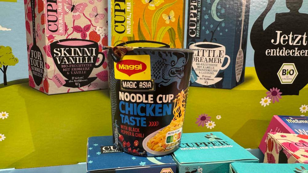 Die getesteten Cup-Noodles vor mehreren Packungen Tee.