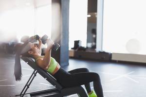 Curlbank-Test: Eine Frau trainiert auf einer Curlbank im Fitnesscenter. 