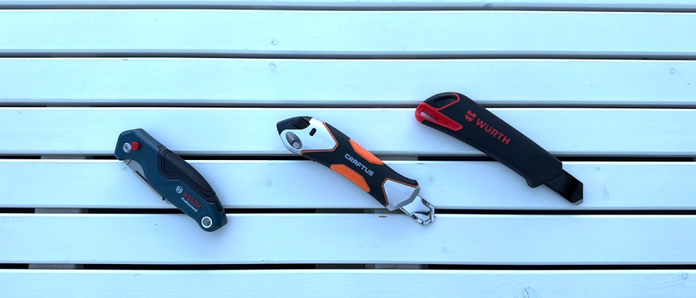 Drei Cuttermesser liegen nebeneinander auf einem Tisch
