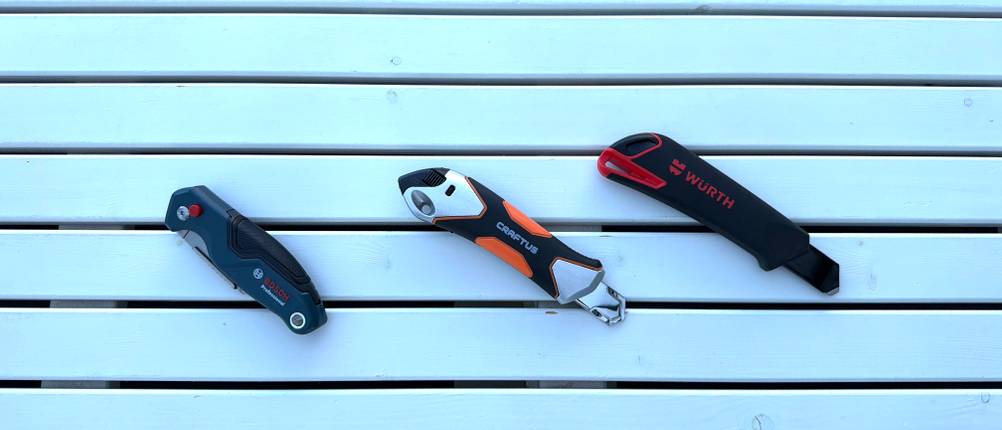 Drei Cuttermesser liegen nebeneinander auf einem Tisch