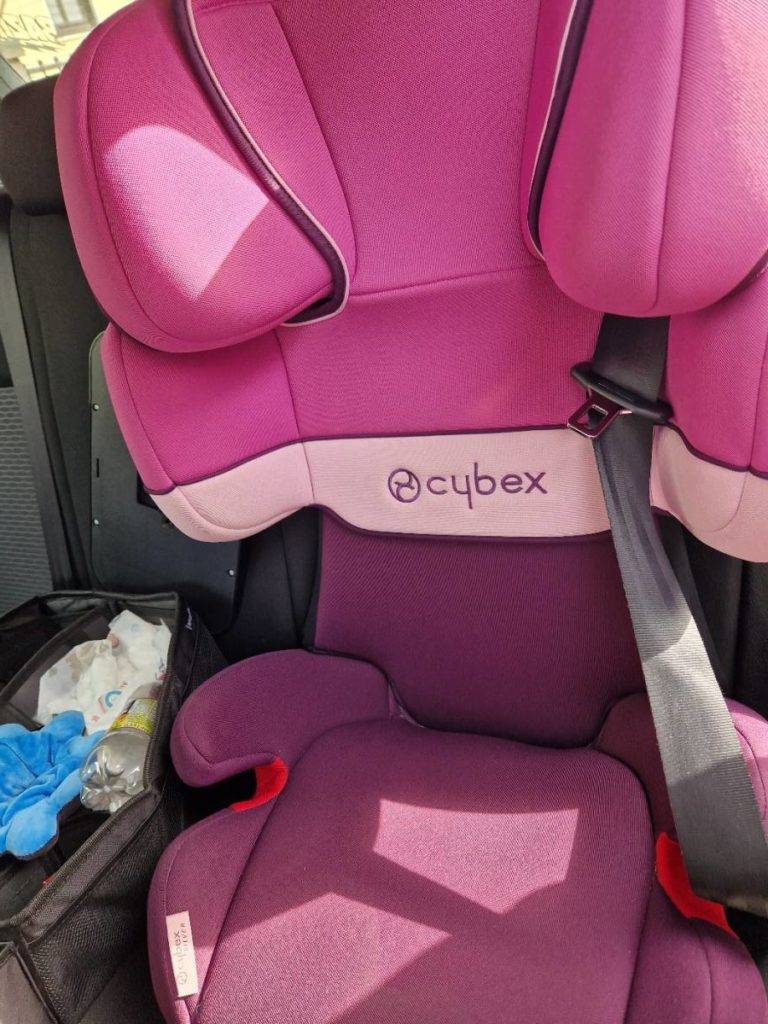 Getestete Sitzerhöhung der Marke Cybex im Rosa-Design befindet sich auf einem hinteren Autositz.