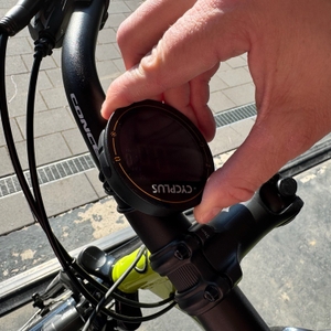 Eine Hand dreht am Display des Cycplus-M2-Fahrradcomputer