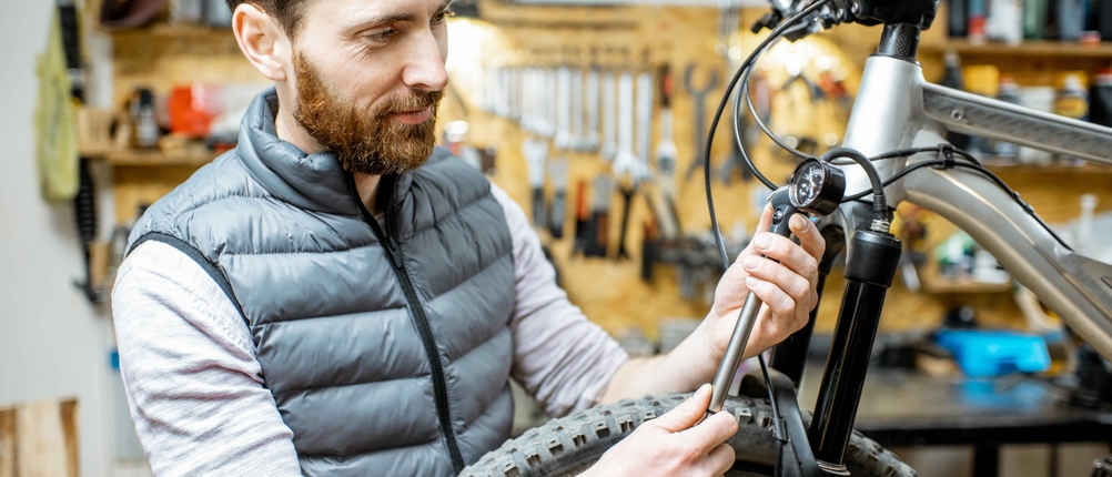 Ein Mann prüft den Druck im Dämpfer einer Frontgabel eines MTBs.