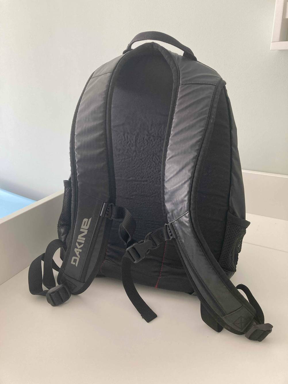 Der Dakine-Rucksack im Test von hinten auf einer hellen Fläche stehend.