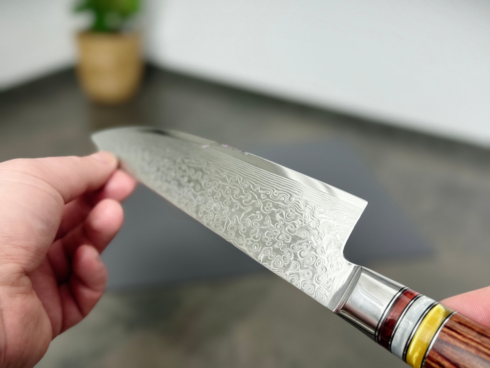 Der Holzgriff des Fanteck Gyuto wird in Nahaufnahme gezeigt. Die Maserung und die Metallringe sind klar und detailreich sichtbar.