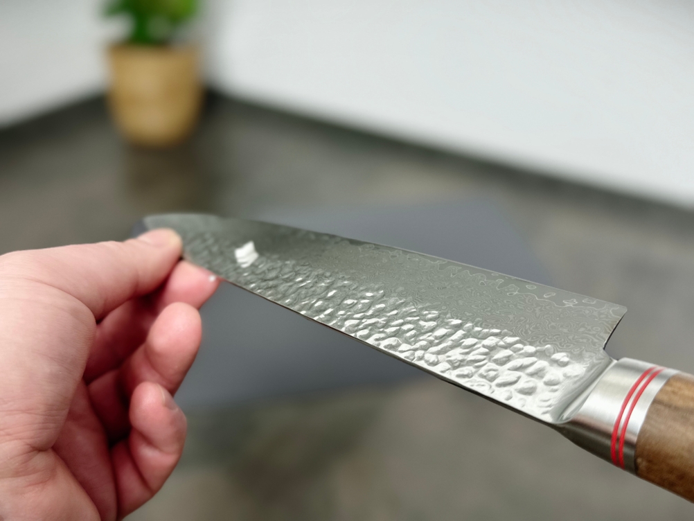 Die Klinge des Schwartzhirsch Caliburn wird seitlich gehalten. Das Damastmuster ist gut zu erkennen, die Struktur wirkt mattiert.