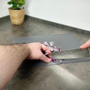 Das Schwartzhirsch Caliburn wird zum Schneiden einer roten Zwiebel verwendet. Die Klinge führt gerade durch das Schnittgut.