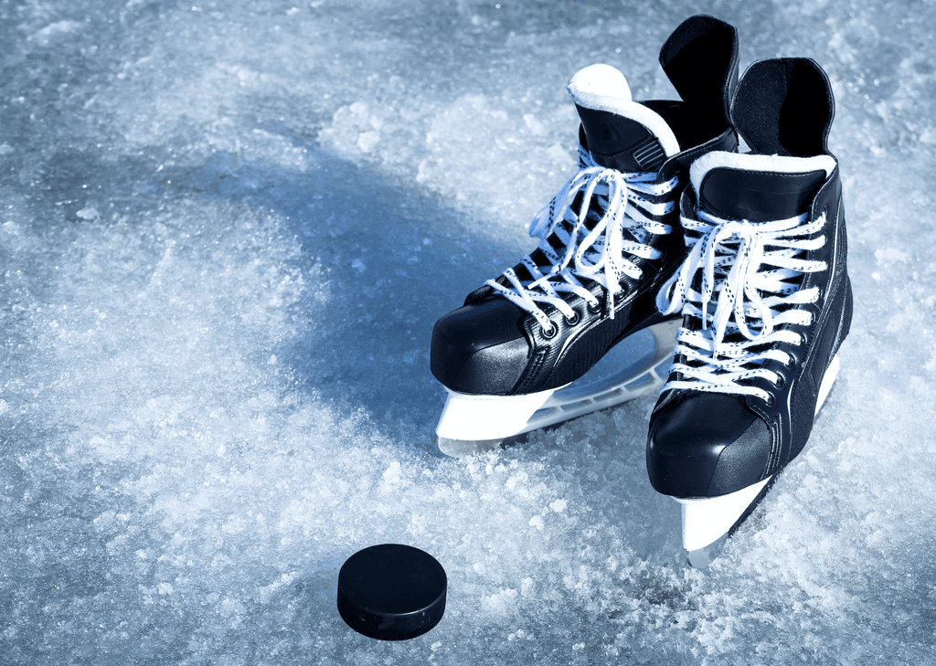 Damen-Schlittschuhe-Test: Schlittschuhe und ein Eishockey-Ball auf Eis. 