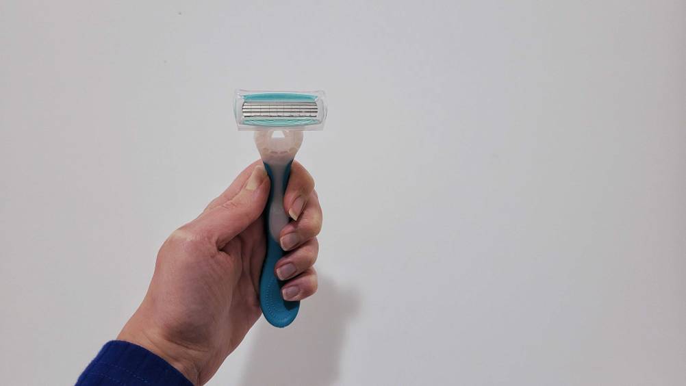 Getestet: Eine Hand hält einen Damenrasierer vor eine hellen Wand.