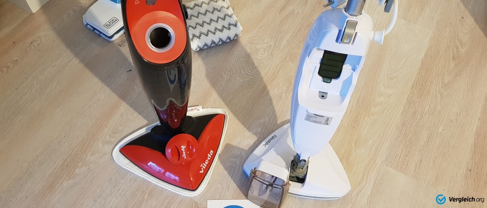 Getestete Dampfbesen: Ein roter und ein weißer Dampfbesen stehen nebeneinander auf hellem Boden.
