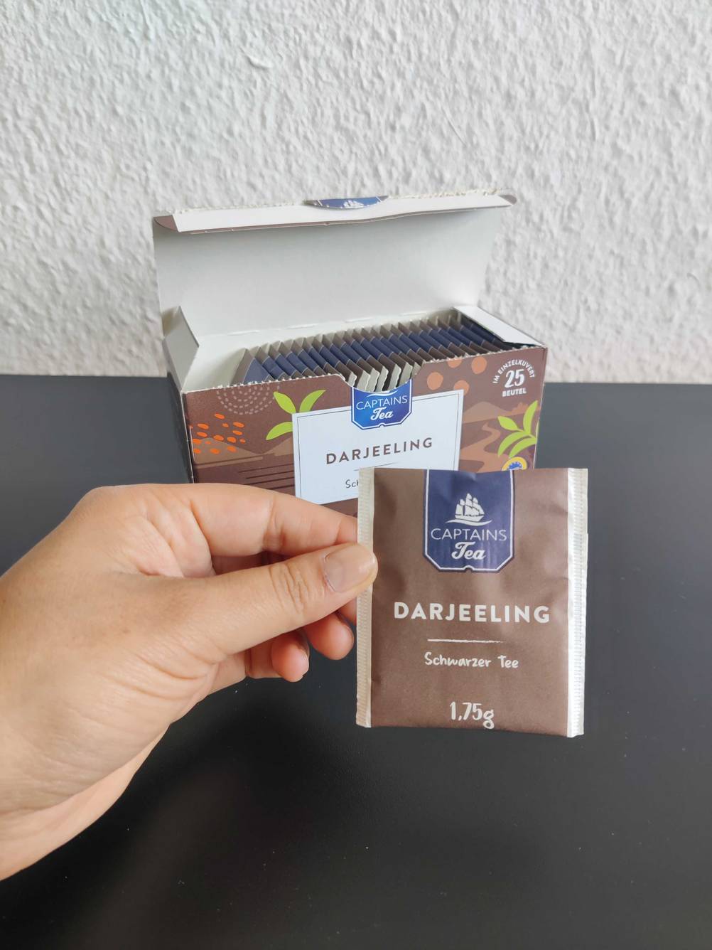 Ein noch verpackter Beutel Darjeeling Tee wird in einer Hand gehalten