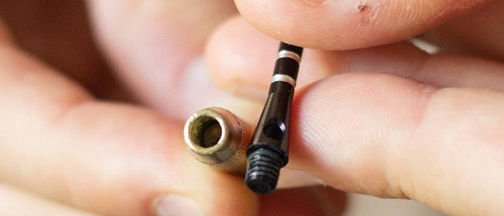 Dartpfeile im Test: verschlissenes Dartpfeilgewinde präsentiert zwischen Daumen und Zeigefinger