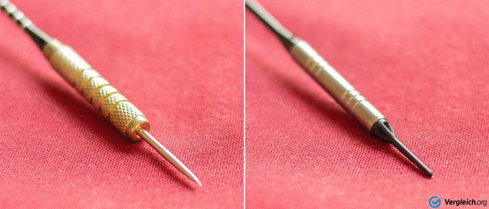 Dartpfeile im Test: zwei Dartpfeile auf rotem Untergrund, links mit Stahl- und rechts mit Kunststoffspitze