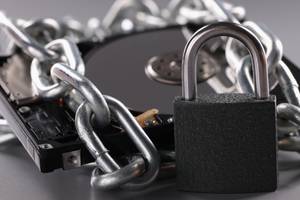 Tests der Datenrettungsprogramme: Eine Festplatte ist von einer Metallkette umschlungen und im Vordergrund steht ein Vorhängeschloss.