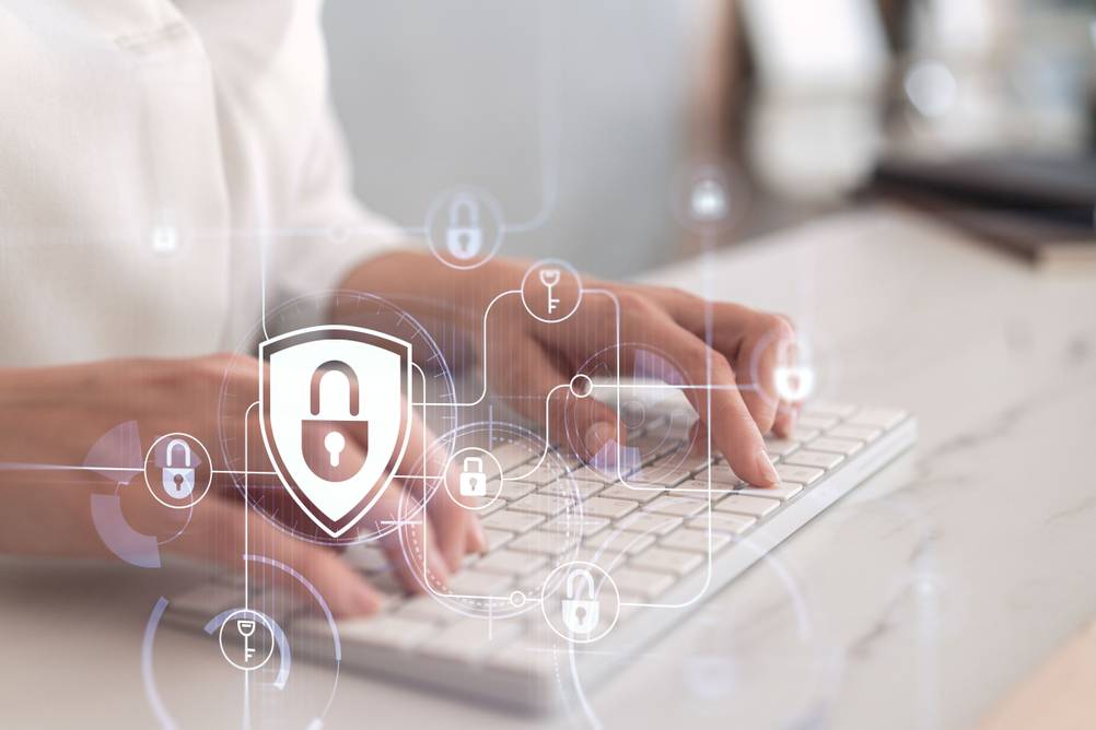 Eine Frau tippt auf einer Tastatur. Im Vordergrund sind Symbole für den Datenschutz zu sehen.