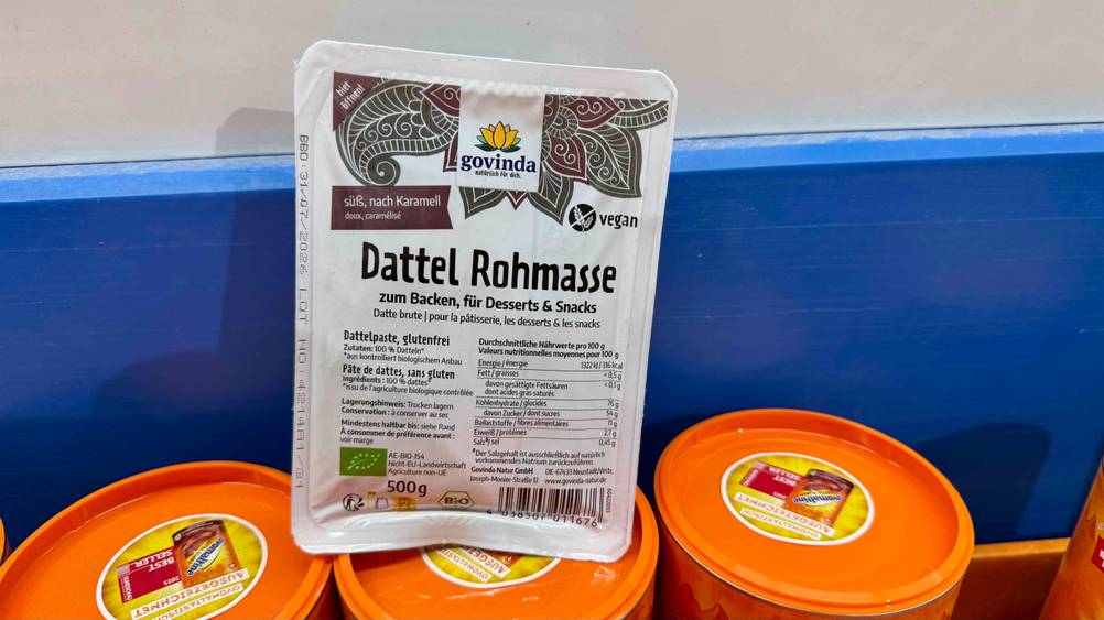 Die getestete Dattelpaste vor einer Wand auf Dosen stehend.