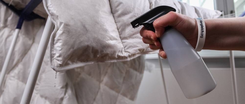 Zum Test wird eine Daunendecke mit Wasser besprüht, um die Trocknungszeit zu messen.