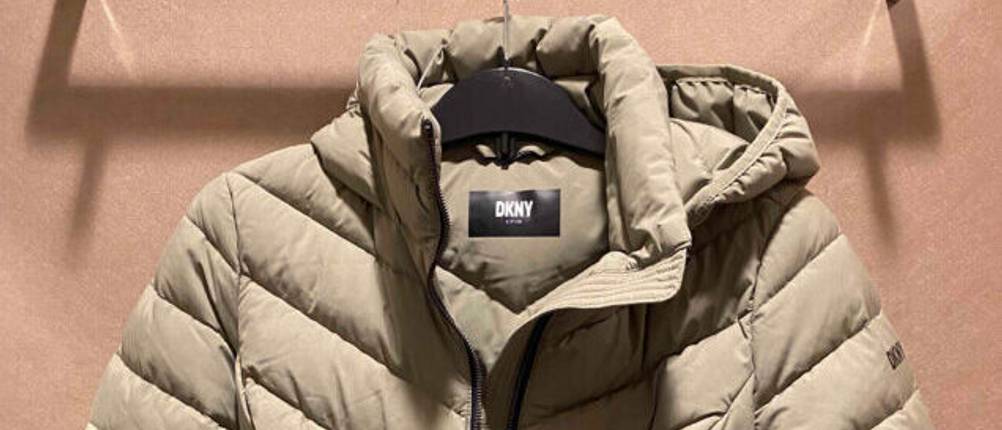 Daunenjacke für Damen von DKNY im Test. Eine Daunenjacke in Beige hängt auf einem Bügel.
