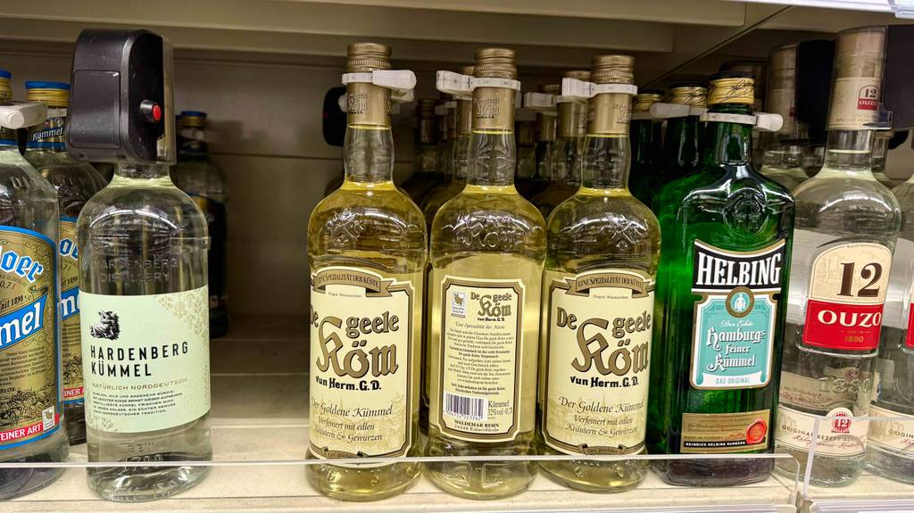 Mehrere Flaschen mit Kümmelschnaps im Test stehen neben anderen Spirituosen in einem Verkaufsregal.