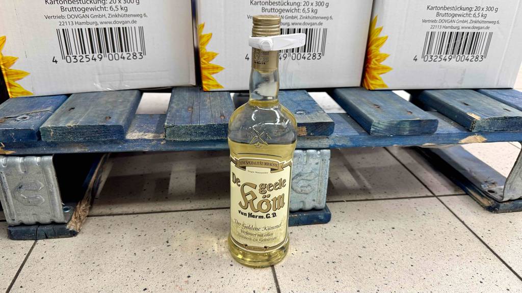 Im Test: Kümmelschnaps in der Flasche steht in einem Supermarkt vor einer Palette mit Kartons.