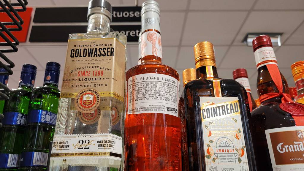 Eine Flasche Rhabarberlikör steht zum testen mit der Rückseite nach vorn zwischen anderen Spirituosen.