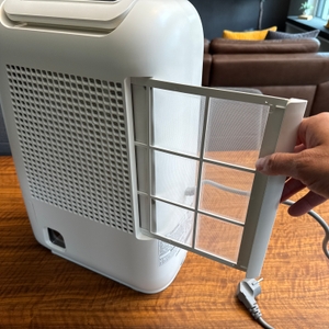 Eine Hand entfernt einen Filter aus dem De'Longhi DEL DNS65