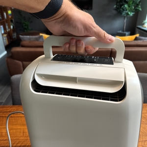 Eine Hand hält den De'Longhi DEL DNS65 an einem Griff fest