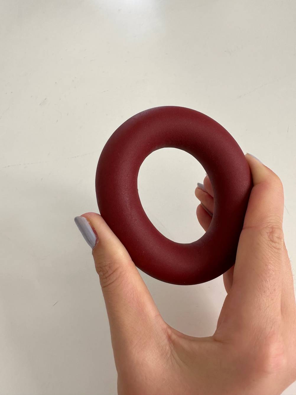 Eine Hand hält einen Handtrainer zum Testen zwischen Daumen und Zeigefinger.