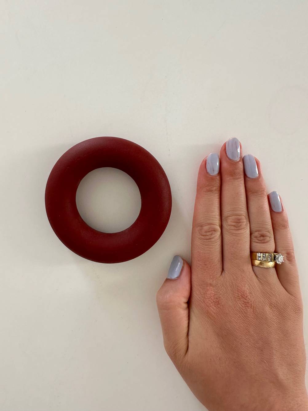 Eine weibliche Hand mit Ring liegt neben einem getesteten Handtrainer.