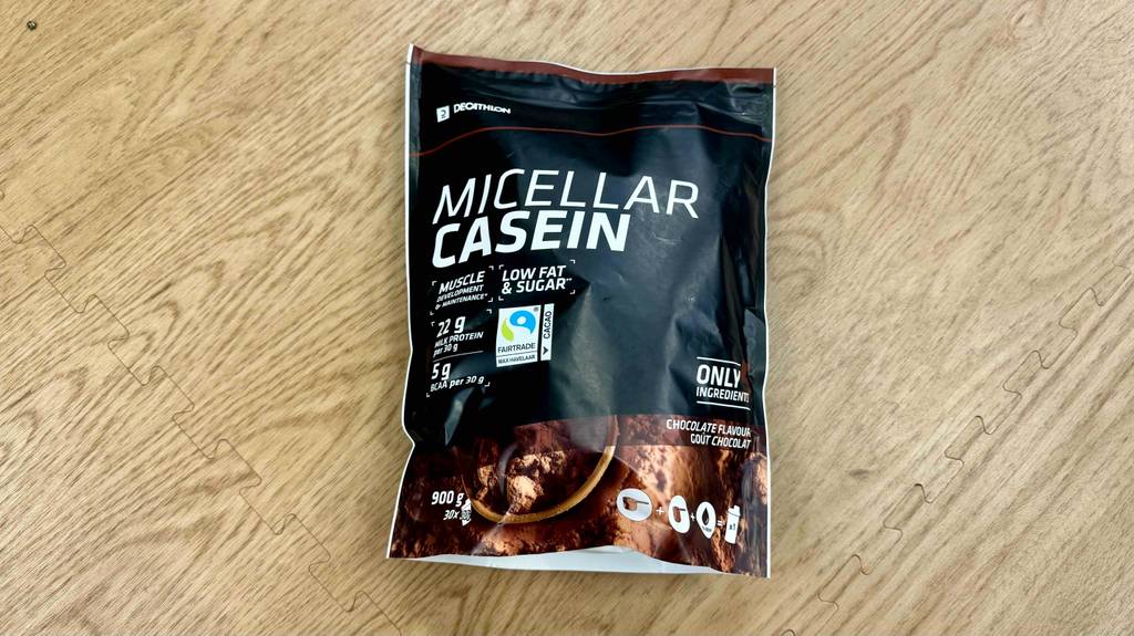 Getestetes Casein befindet sich in einer wiederverschließbaren 900-g-Packung auf einem Holzboden.