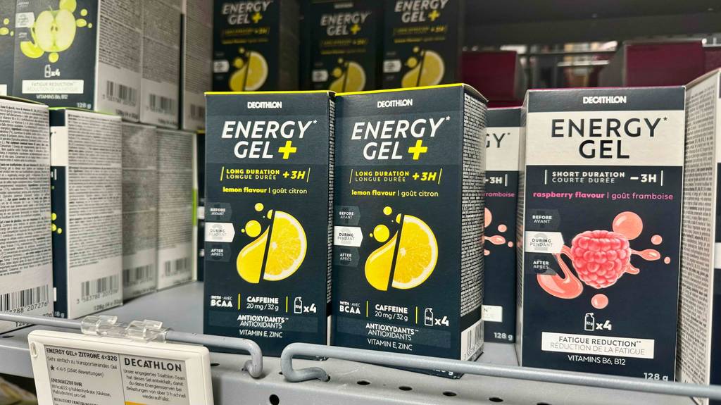 Mehrere schwarze Verpackungen der Marke Decathlon mit Energiegel im Test stehen auf einem Verkaufsregal.