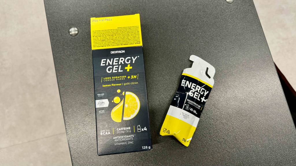 Im Test: Energiegel in schwarzer Verpackung mit Zitronen-Aufdruck befindet sich neben einem Trinkbeutel auf einer schwarzen Oberfläche.
