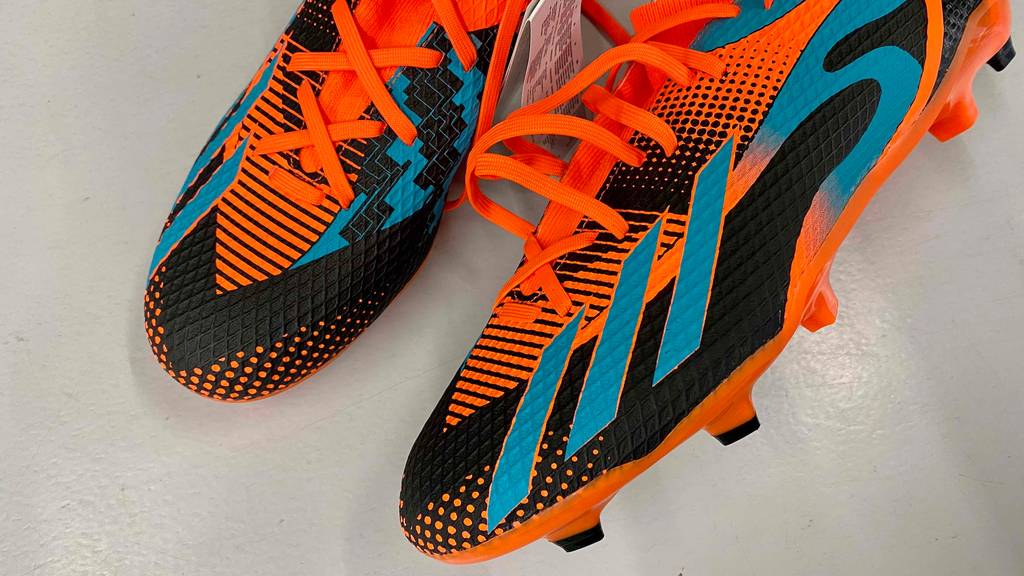 Ein paar getestete Fußballschuhe für Herren, einer davon liegt etwas quer mit Stollenansicht.