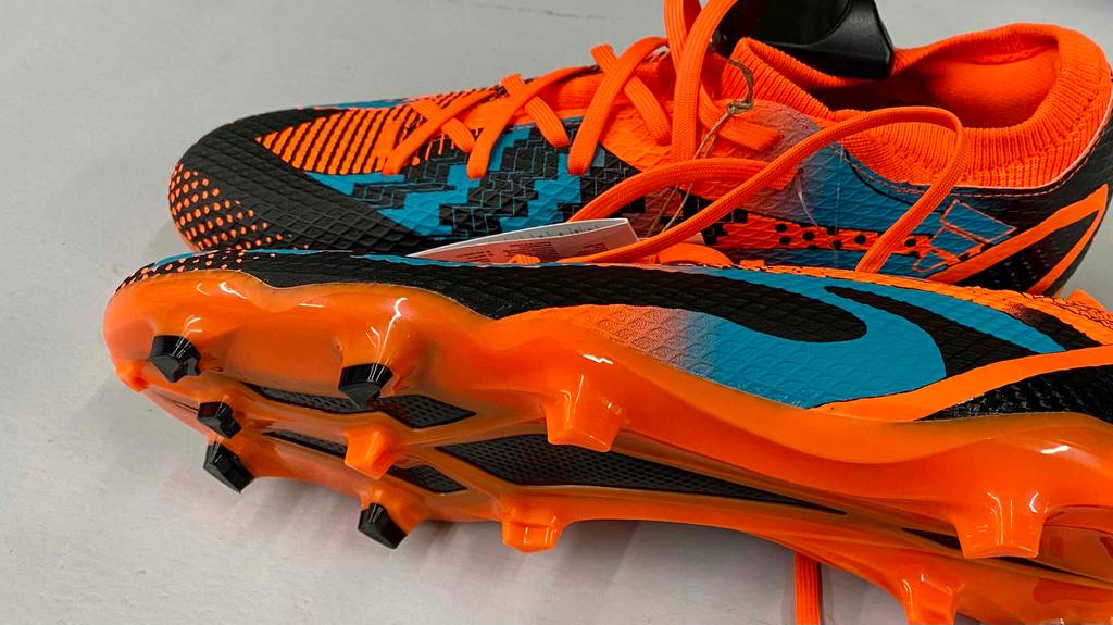 Ein getesteter Herren-Fußballschuh liegt mit der Sohle und den Stollen nach vorn vor dem zweiten.