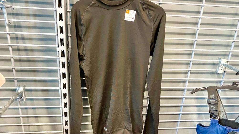 Kompressionsshirt Herren getestet: Ein Shirt hängt an einem Bügel an einer Metallsprossenwand.